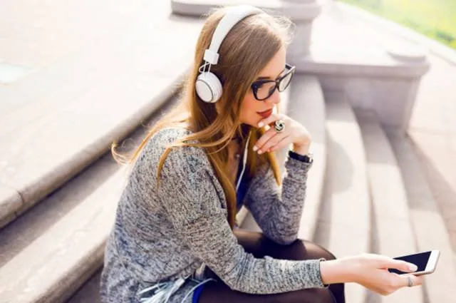 Красивая молодая девушка слушает музыку в наушниках.